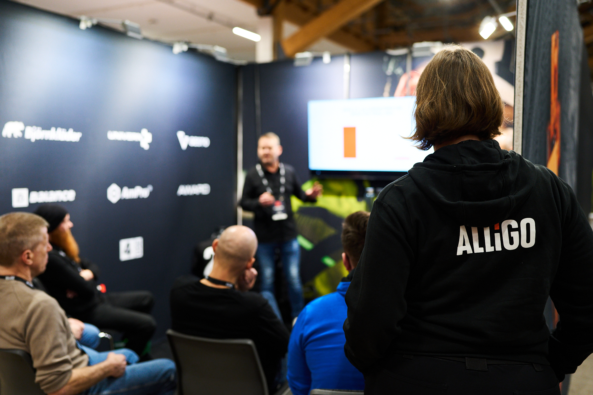 An Alligo employee attending a presentation at an indoor event