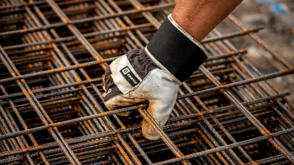 Gloved hand grips rusty construction rebar