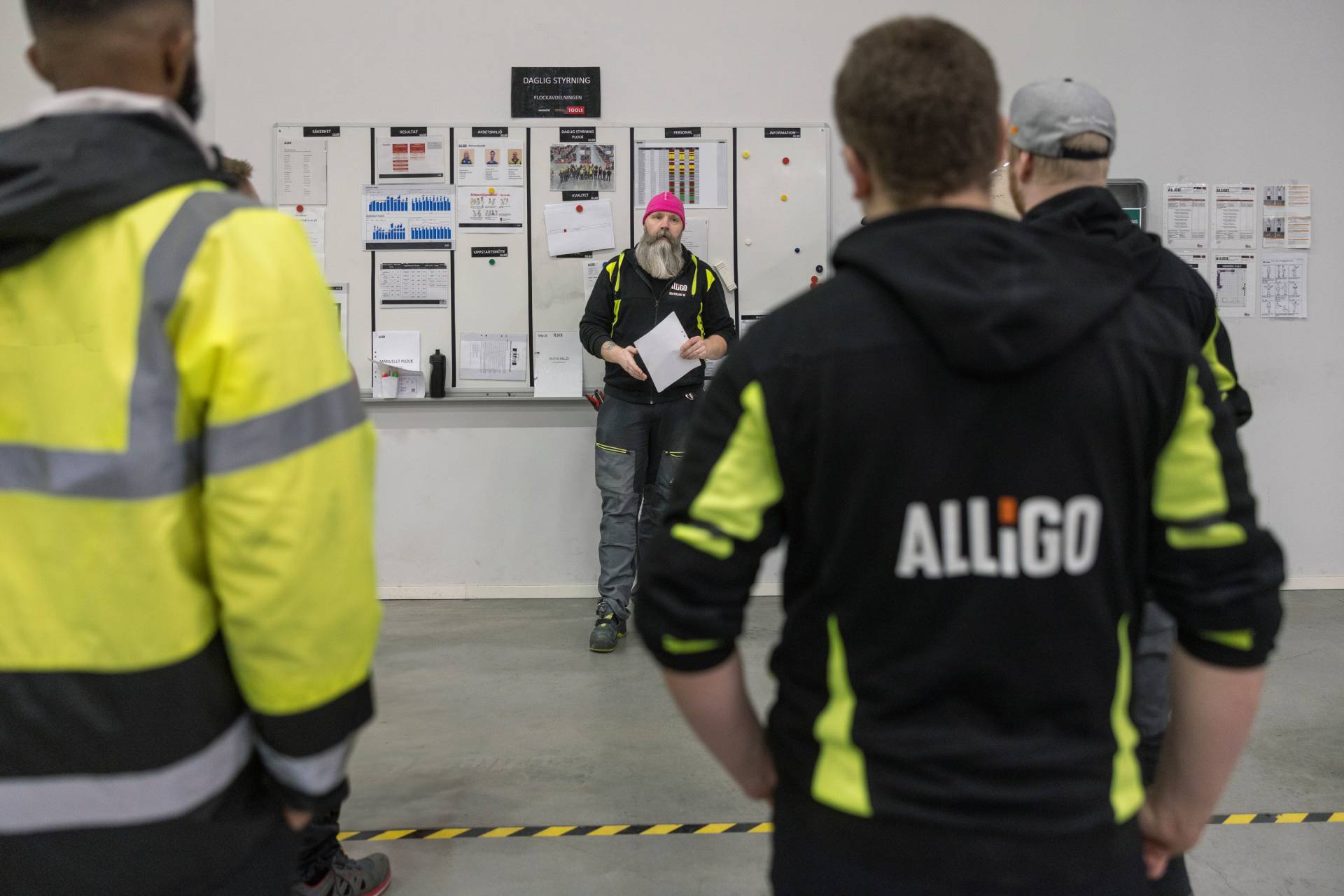 Team briefing in front of a planning board at an Alligo workplace