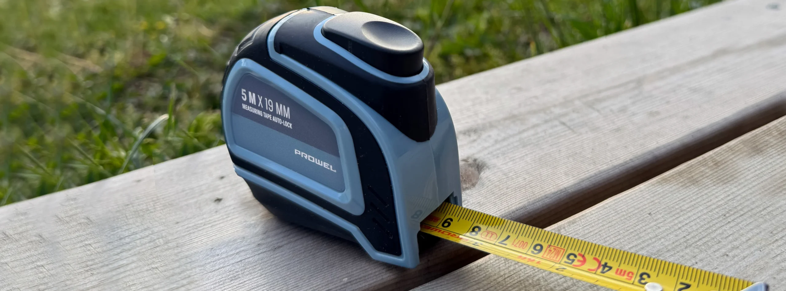 Measuring tape extended on wooden plank outdoors, showing measurement