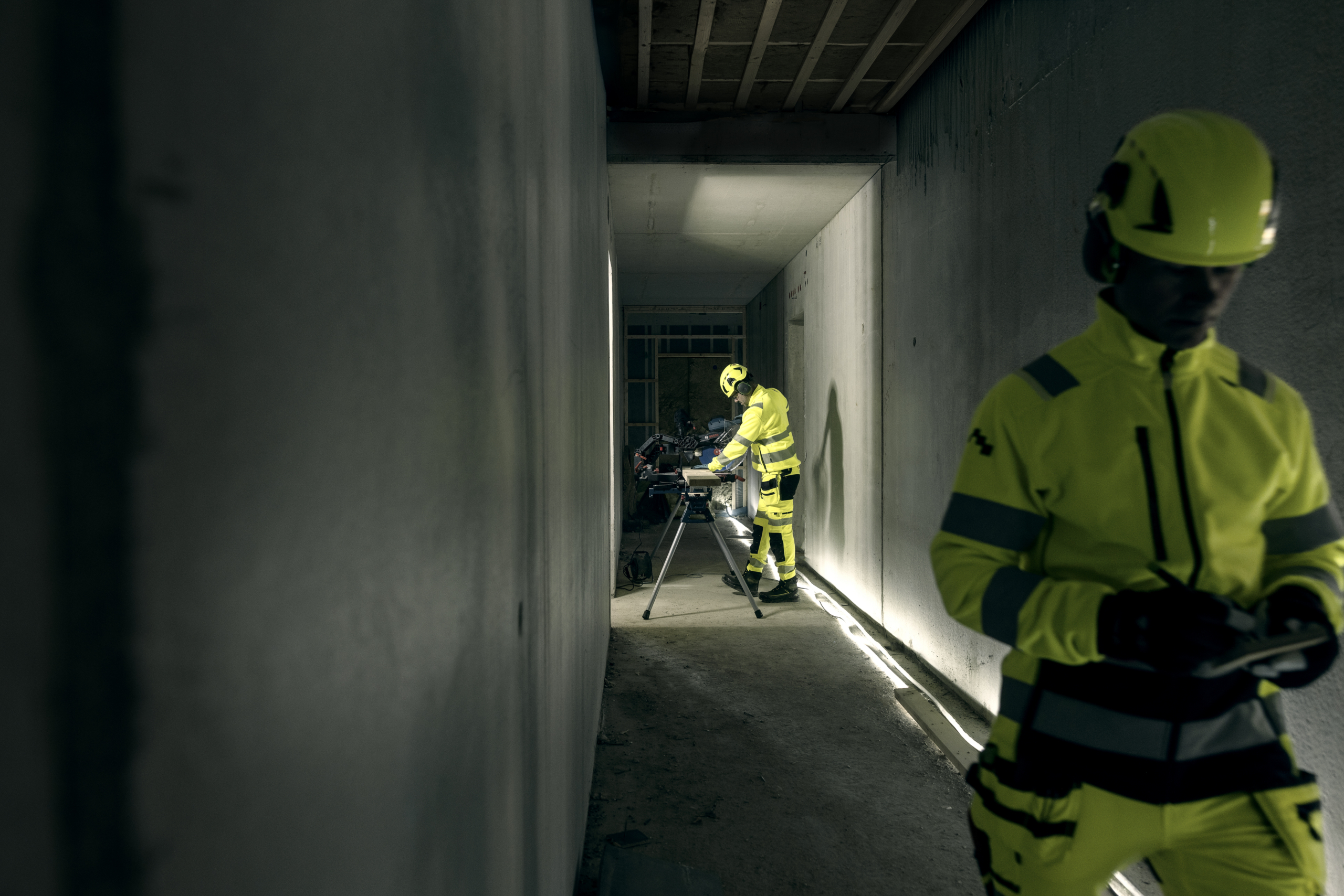 Arbetare med handskar hanterar säkerhetslina och sele vid höghöjdsarbete