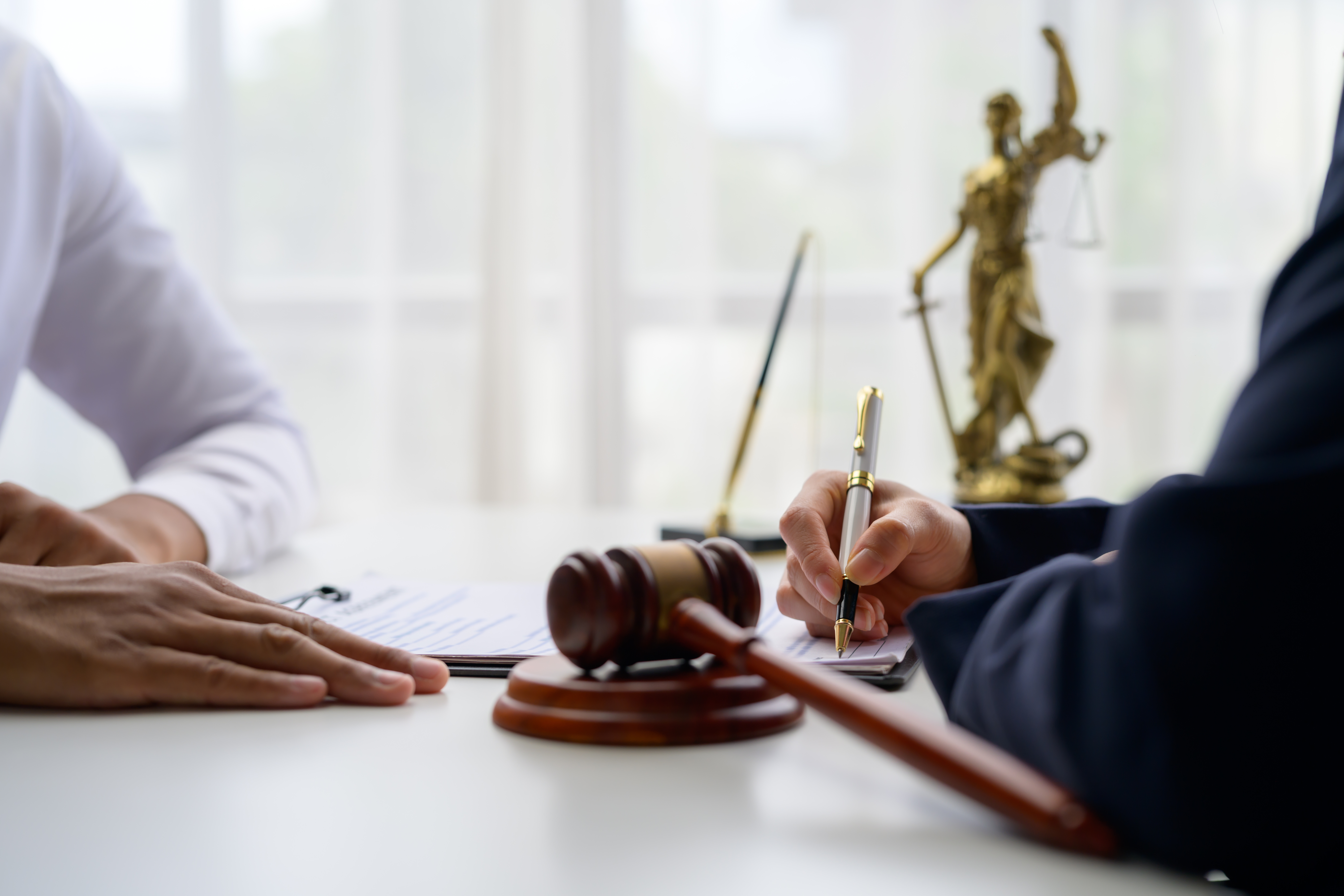 Person signing a document with a judge’s gavel nearby