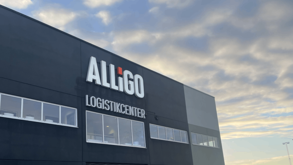 Alligos logistikcenter med logotyp, stora fönster och solnedgång i bakgrunden