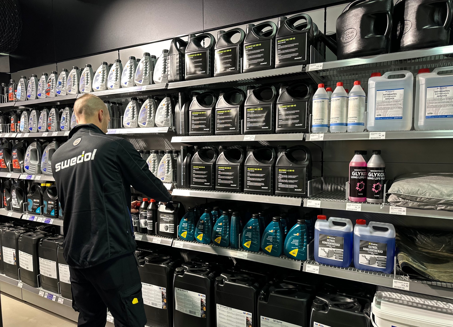 En Swedol-anställd ordnar olje- och kylvätskebehållare på butikshyllor